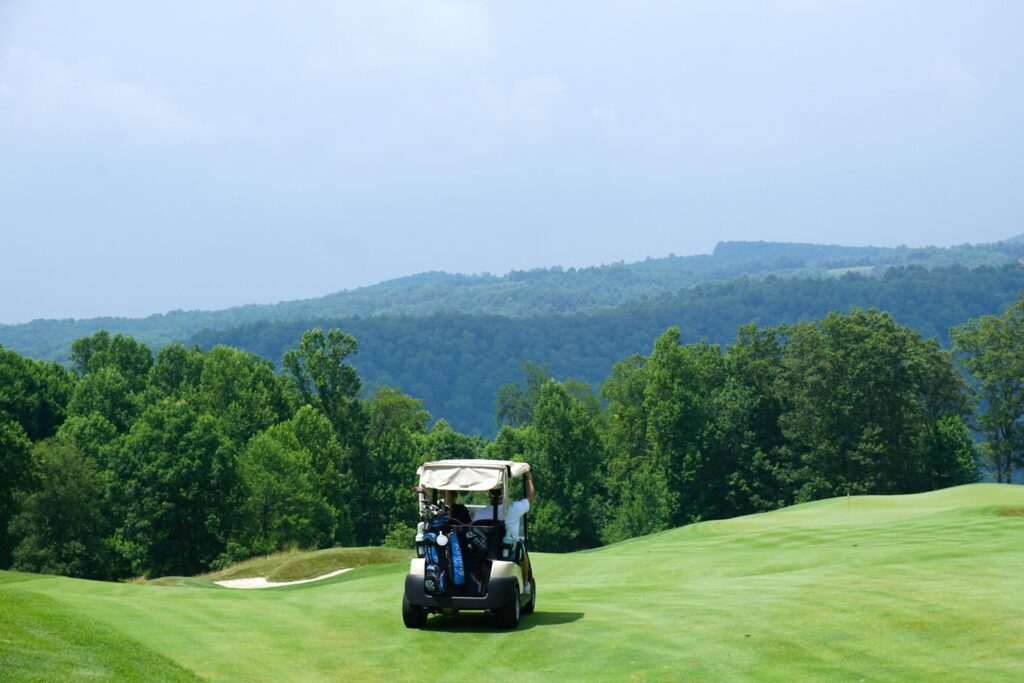 Golf corporativo: buggy en un campo de golf rodeado de colinas