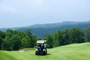 Golf corporativo: buggy en un campo de golf rodeado de colinas