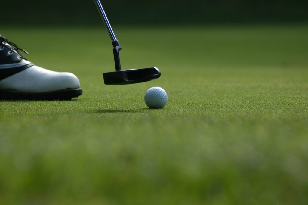 Golfista a punto de patear la bola en el green