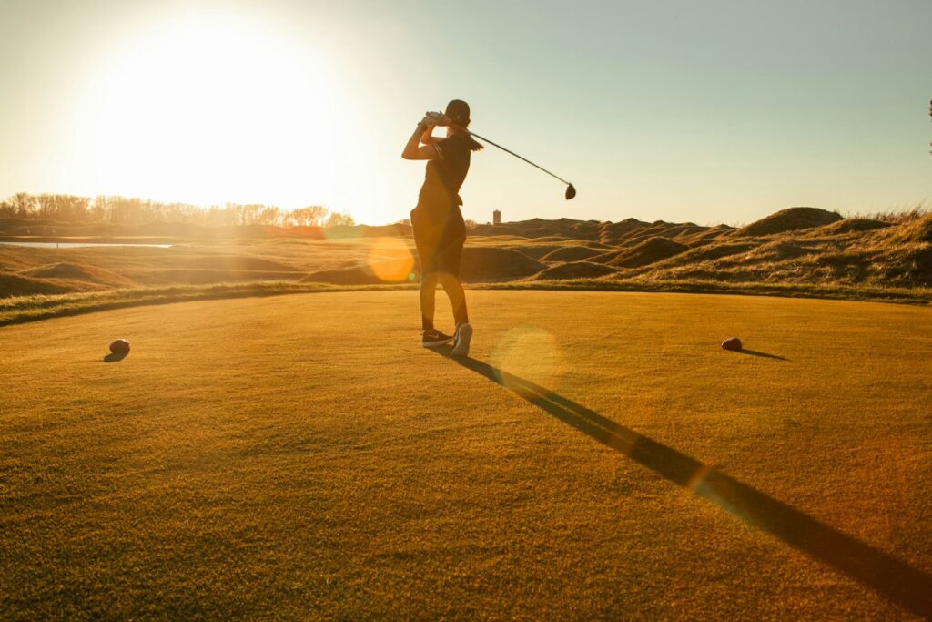 Golfista ejecutando un swing al atardecer